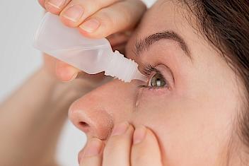Woman putting drops in her eyes to treat glaucoma