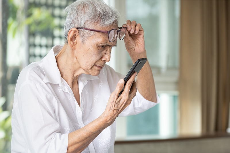 Older woman struggling to read her phone because of her cataracts